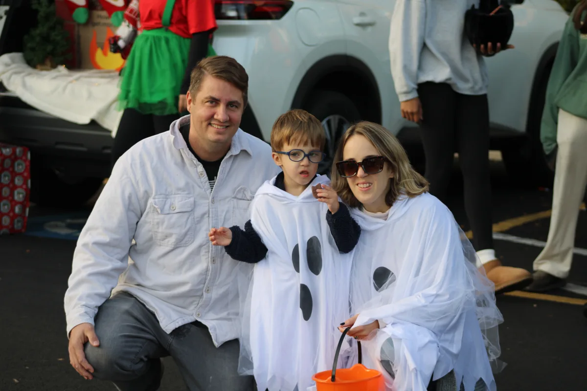 A kid and his parents dress up as ghosts for Halloween at Trunk or Treat. There were many different costumes at this event, with both kids and parents dressing up.