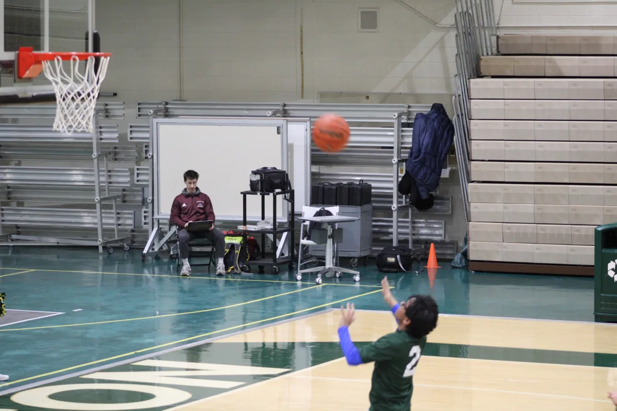 John Falcon '25 shoots the ball in front of the basket. Falcon was a top scorer, earning the team 14 points throughout the game.