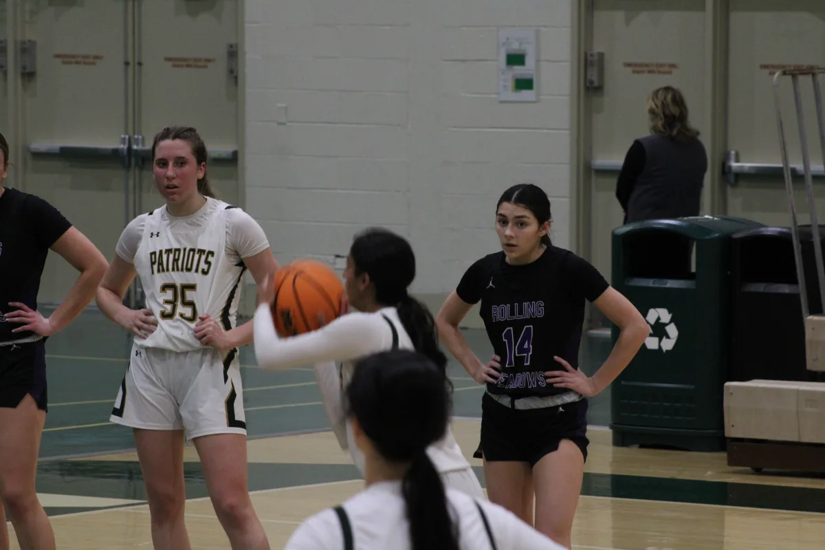 Nisha Musunuri '25 shoots a free throw in front of her teammate Reese McLelland '28 and Rolling Meadows player Anna Andriano. Musunuri and teammate Sydney Rosland '25 earned 31 points for the team.