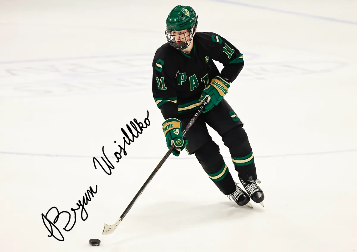 An autographed image of Bryan Wojdelko ’25 in control of the puck as he moves across the ice. Wojdelko is the assistant captain of the varsity green boys hockey team. Photo courtesy of Joel Lerner.